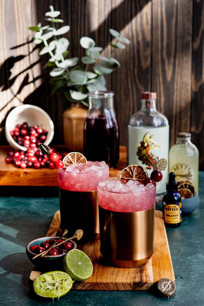 A photograph shows two cranberry Moscow mule mocktails, photographed by Orlando Beverage Phtographer, Lindsey Neumayer.